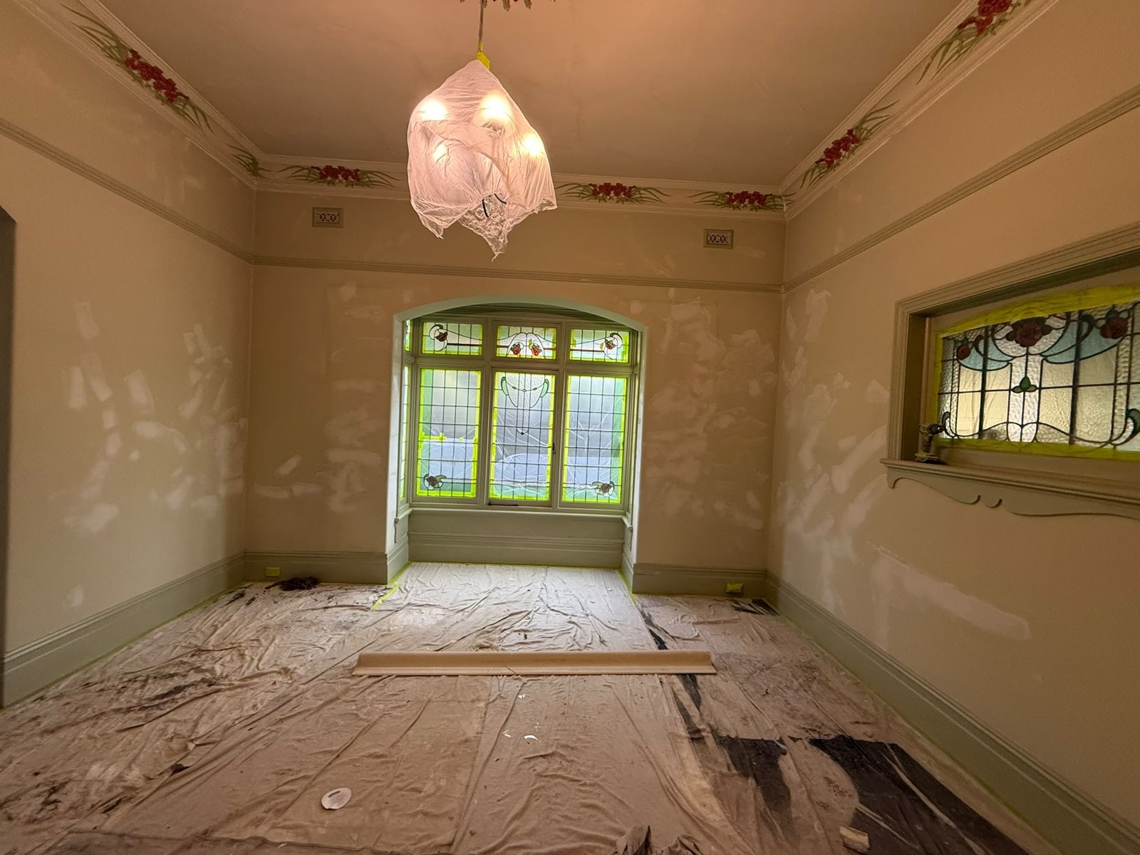 Period room with localised wall patches, stained-glass windows and floor coverings during preparation
