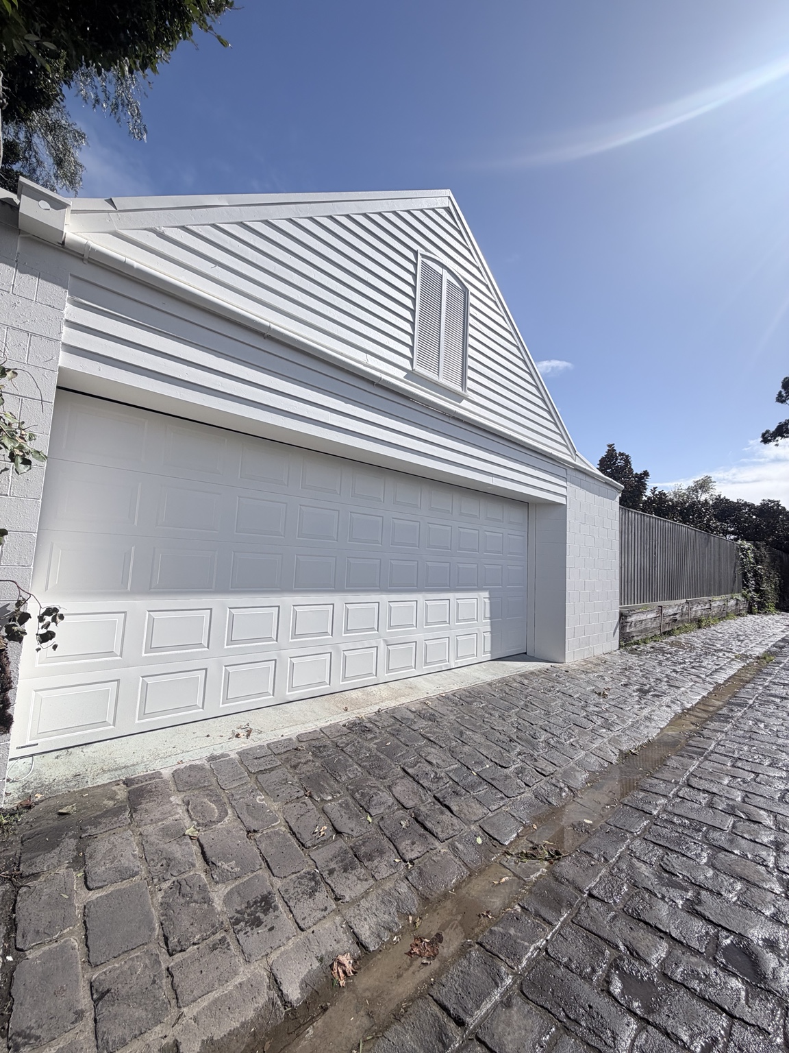 Completed Malvern garage repaint viewed from the side, showing the gable, garage door and masonry